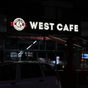 illuminated channel letters on wooden sign for West Cafe