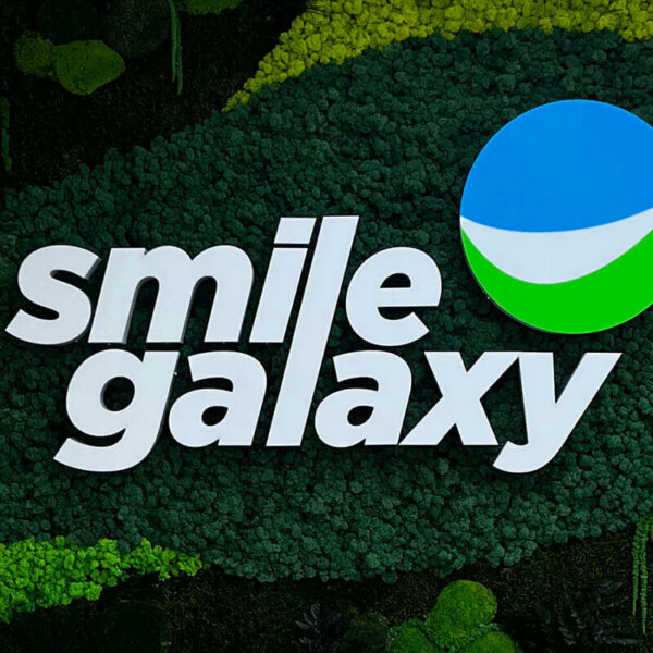 Smile Galaxy illuminated channel letters on a Scandinavian moss wall